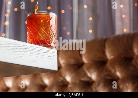 Bicchiere di gustoso cocktail di whiskey fresco e forte decorato con buccia d'arancia sullo sfondo luminoso. Foto Stock