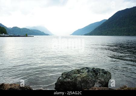 Vista dalla costa rocciosa di un grande lago adagiato sulle montagne in tempo nuvoloso. Lago Teletskoye, Altai, Siberia, Russia. Foto Stock