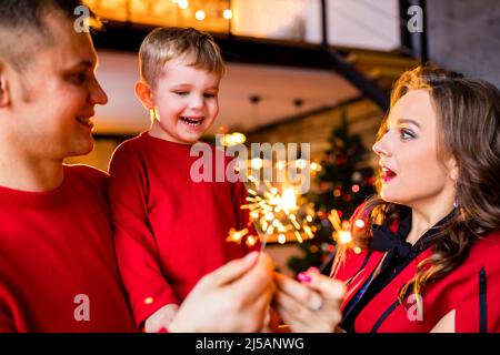 Famiglia giovane che soggiorna a casa durante le vacanze di Natale e che ha una festa di quarantena in soggiorno Foto Stock