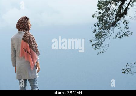 Il punto di vista posteriore di una giovane donna musulmana godendo nel tempo nebby-fogy Foto Stock