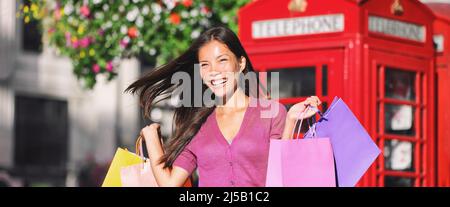 Donna asiatica felice shopping a Londra a piedi su Oxford Street con molteplici borse regalo da vendita negozio. Ragazza sorridente in rosa per la primavera. Panoramica Foto Stock