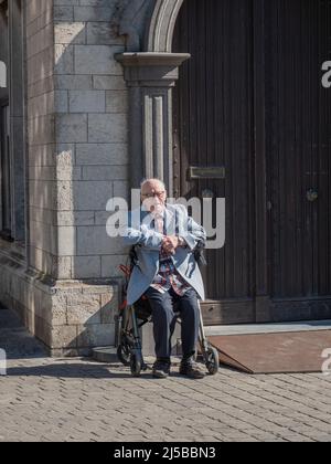 Anversa, Belgio, 17 aprile 2022, un anziano baldante sta riposando sul suo camminatore in un edificio storico nella piazza del mercato di Anversa Foto Stock