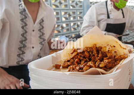 Taco uomo o TAQUERO preparare tacos sulla strada come parte della cultura Street food del Messico, un Taco su un piatto per un cliente. street food fotografia Foto Stock