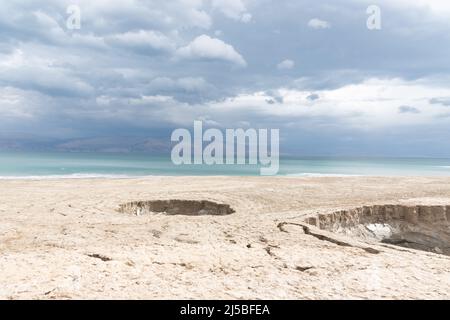 Buca piena di acque turchesi, vicino alla costa del Mar Morto. Foro formato quando il sale sotterraneo è dissolto da intrusione di acqua dolce, dovuto la caduta continua del livello del mare. . Foto di alta qualità Foto Stock