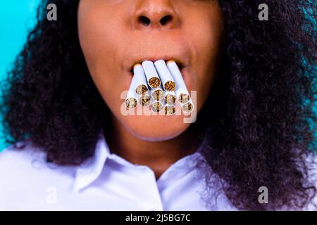 donna afroica che vince con problemi di nicotina addicted, smetta di fumare studio sfondo blu Foto Stock