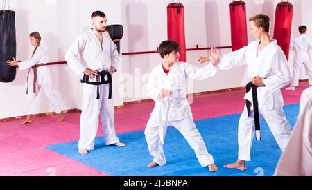 I bambini che lavorano in coppia padroneggiano le nuove mosse del karate Foto Stock