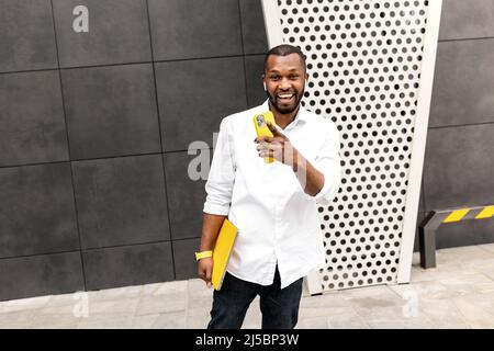 Felice maschio freelance o studente utilizzando il tablet, ha ricevuto grandi notizie sulla promozione di lavoro o superato l'esame, sorridendo. Un uomo d'affari afroamericano molto gioiato Foto Stock