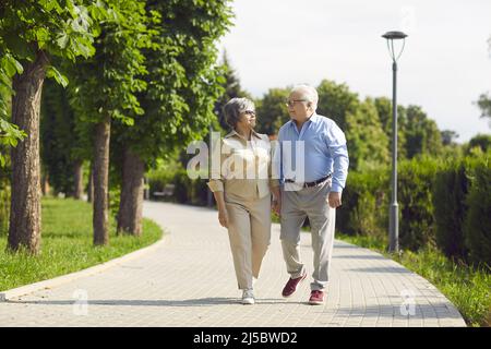 Coppia allegra che si è divertita in un parco cittadino a piedi, ridendo e godendo di una giornata di sole. Foto Stock