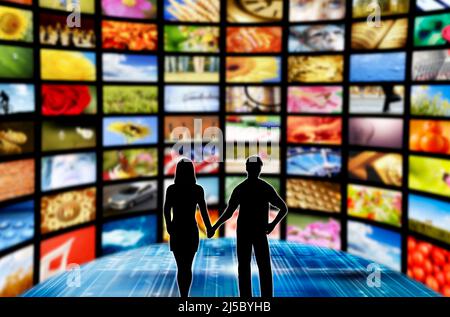 coppia uomo e donna in una stanza con molti schermi, trasmissione e streaming online concetto Foto Stock