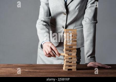 Uomo d'affari che rimuove il blocco di legno dalla torre Foto Stock