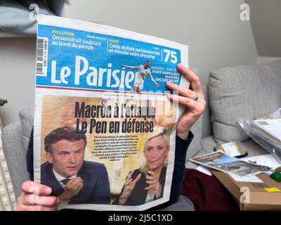 Parigi, Francia - 21 apr 2022: Donna che legge sul divano letto le Parisien giornale dopo dibattito tra Marine le Pen e il presidente francese Emmanuel Macron - elezione presidenziale del 2022 Foto Stock