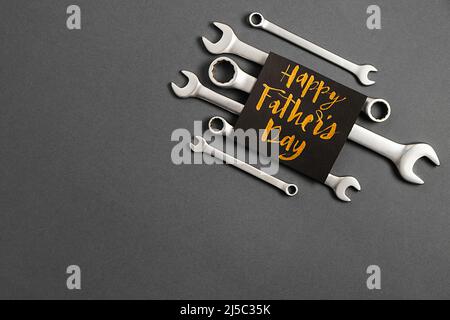 Composizione creativa a disposizione piatta con chiavi combinate, biglietto con frase Happy father's day e retro elegante carta nera cabina fotografica props baffi Foto Stock