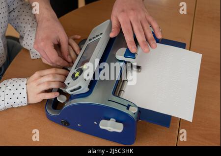 Un uomo insegna a una donna cieca a scrivere su una macchina braille. Foto Stock