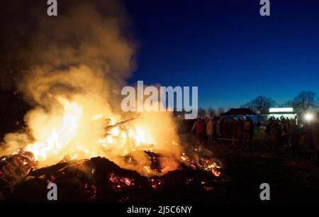 16 aprile 2022, Sassonia-Anhalt, Kathendorf: I celebratori stanno accanto ad un fuoco pasquale la sera. Foto: Soeren Stache/dpa Foto Stock