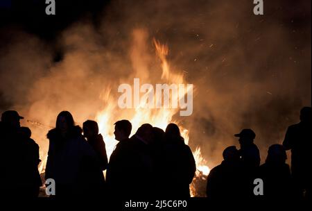 16 aprile 2022, Sassonia-Anhalt, Kathendorf: I celebratori si trovano di fronte a un incendio pasquale la sera. Foto: Soeren Stache/dpa Foto Stock
