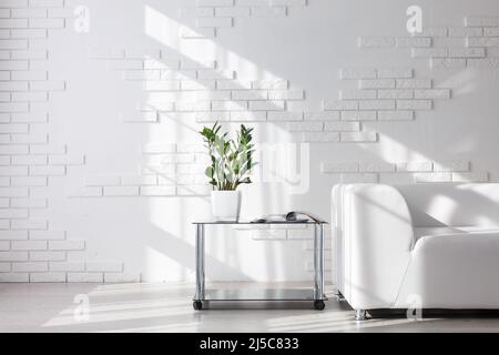 Interno luminoso e minimalista con divano bianco accanto alla finestra e sgabello nero Foto Stock