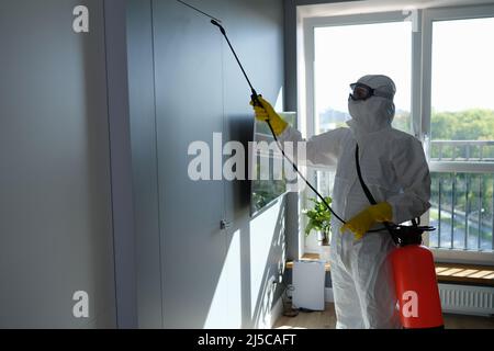 Operaio in tuta protettiva e maschera spray sostanze chimiche in ambienti interni Foto Stock