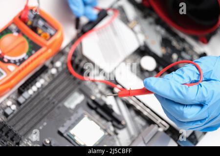 Il tecnico sta testando la riparazione dei chip della scheda madre Foto Stock