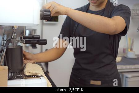 Primo piano mettere l'acqua calda in un bicchiere. Preparare una tazza di caffè in una macchina per il caffè, il vapore e la tazza. Foto Stock