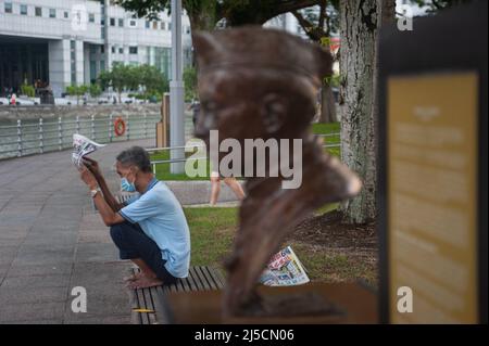 28 maggio 2020, Singapore, Repubblica di Singapore, Asia - un uomo che indossa una guardia della bocca legge un giornale durante il coprifuoco in mezzo alla crisi di Corona (Covid-19) sulle rive del fiume Singapore, poco prima della prima fase di misure di allentamento e riapertura. In primo piano è il busto dell'ex primo ministro indiano Nehru. [traduzione automatizzata] Foto Stock