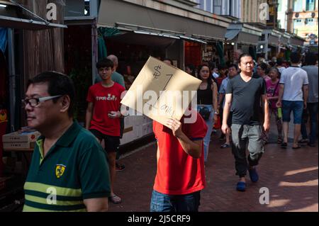 24 gennaio 2020, Singapore, Repubblica di Singapore, Asia - Un fornitore tiene un cartello di cartone con un'offerta di risparmio all'inizio della crisi di Corona mentre la gente cammina attraverso un bazar di strada trafficato nel quartiere di Chinatown della città, che si tiene ogni anno per il Capodanno cinese. Questo avviene poco dopo che la città-stato ha confermato la sua prima infezione con il coronavirus (Covid-19). [traduzione automatizzata] Foto Stock