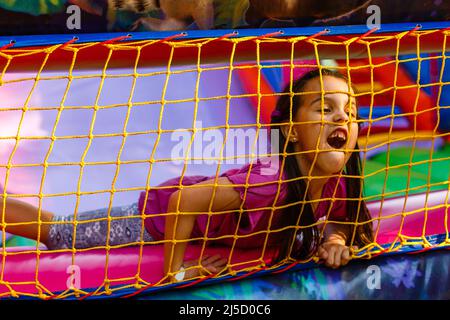 Un bambino allegro gioca in un castello gonfiabile Foto Stock