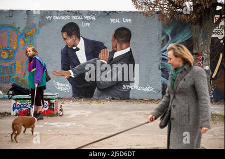 '30.03.2022, Berlino, Germania, Europa - due donne camminano i cani mentre sullo sfondo i graffiti dell'artista EME Freethinker sono visti su un segmento del muro di Berlino nel Mauerpark di Berlino nel quartiere Prenzlauer Berg, L'attore che mostra Will Smith schiaffa il comico Chris Rock sul palco ai premi dell'Accademia 94th dopo che ha fatto il divertimento di sua moglie Jada Pinkett Smith. Will Smith vinse più tardi il primo Oscar nella sua carriera per il ruolo del padre dei giocatori di tennis Venus e Serena Williams nel film ''King Richard''. [traduzione automatizzata]' Foto Stock