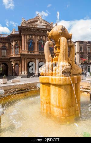 Fontana dei Delfini, Centro Catania. Piccola fontana a tema di delfini con il teatro dell'opera sullo sfondo. Piazza Teatro. Centro di Catania. Sicilia. Italia. (129) Foto Stock