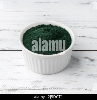 Spirulina polvere di alghe in una ciotola su tavola di legno. Foto Stock