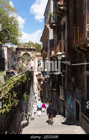 La gente, compresa una famiglia turistica, scende in discesa su Via Penninello, Città di Catania, Sicilia. Italia. Vista da Via Crociferi. (129) Foto Stock