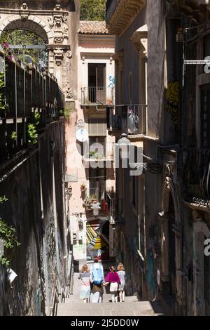 La gente, compresa una famiglia turistica, scende in discesa su Via Penninello, Città di Catania, Sicilia. Italia. Vista da Via Crociferi. (129) Foto Stock