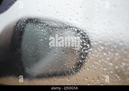 La pioggia cade sullo specchio e sul finestrino della vettura nelle giornate piovose Foto Stock