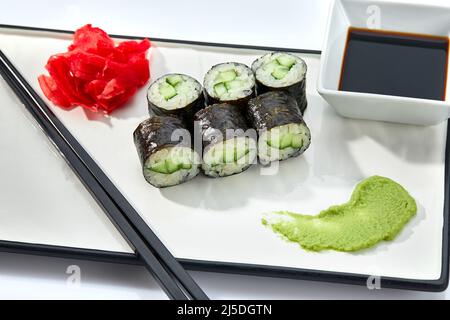 Sushi roll della California o di Philadelphia serviti su un vassoio bianco su sfondo bianco. Concetto di cucina Giapponese, ricetta tradizionale. Foto Stock