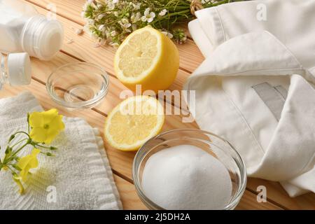 Assaggi di prodotti per la pulizia di abiti fatti in casa ed ecologici su tavola di legno con camicia e asciugamano. Vista dall'alto. Composizione orizzontale. Foto Stock