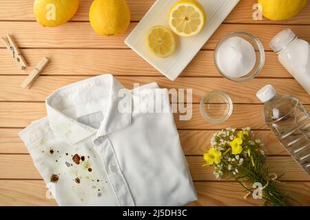 Confronto e concetto di pulizia e lavaggio dei vestiti con prodotti naturali ed ecologici con camicia semi sporca e semi pulita su legno Foto Stock