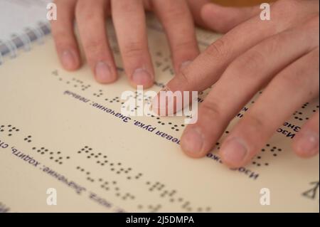 Uomo ipovedente che legge un libro braille. Foto Stock