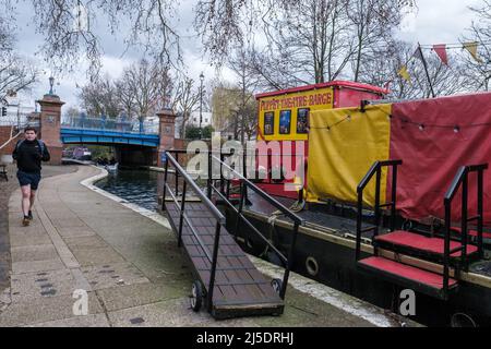 L'uomo cammina lungo il sentiero del canale di Regent a Blomfield Road, Little Venice vicino alla Barge del Teatro dei Pupi. Warwick Avenue sullo sfondo. Londra occidentale, Regno Unito. Foto Stock