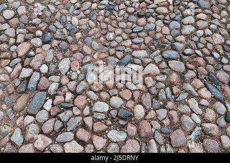 Pavimentazione stradale in ciottoli con pietre di granito rotonde, vista dall'alto, texture foto di sfondo Foto Stock