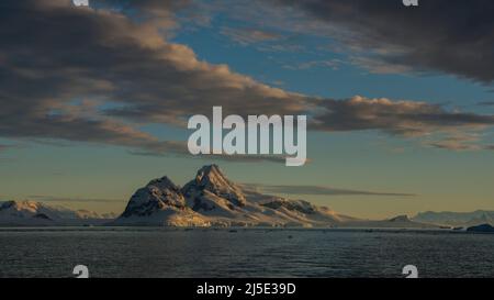 Stupendo paesaggio polare con acque calme, ghiacciai, montagne e alba, Antartide Foto Stock