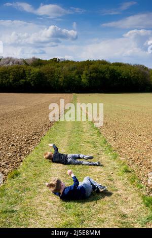 Due ragazzi che si rotolano su una collina nella campagna britannica Foto Stock