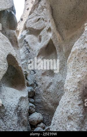 Gli anelli di arrampicata aiutano gli escursionisti a salire su uno scivolo stretto in un canyon slot presso la Mojave National Preserve sul sentiero Rings Loop, un'escursione per famiglie. Foto Stock