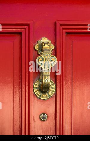 Ornati, decorativa della porta in ottone respingente sul rosso in legno dipinto porta anteriore con spy glass viewer, REGNO UNITO Foto Stock