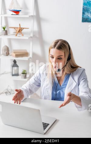 Terapista vocale in cuffia con videochiamata sul computer portatile in sala di consulenza Foto Stock