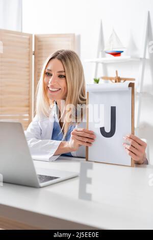 Buon logopedist tenere appunti durante la videochiamata sul laptop in sala di consulenza Foto Stock