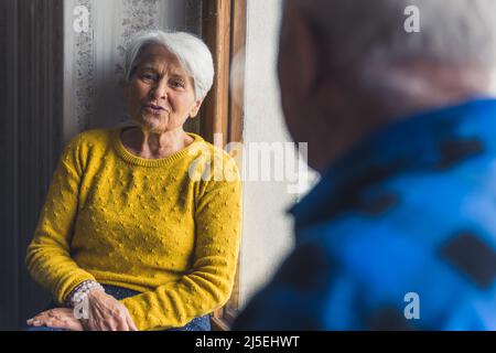 coppia anziana graziosa che parla a vicenda su una finestra-davanzale medio colpo all'interno il concetto di supporto della gente anziana. Foto di alta qualità Foto Stock