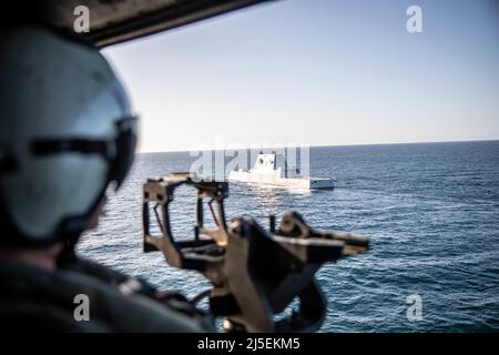 CPL. Marino USA Rylan Wolfe a UH-1Y Venom Crew Chief with Marine Light Attack Helicopter Squadron 169, Marine Aircraft Group 39, 3rd Marine Aircraft Wing (MAW), osserva l'area vicino alla USS Michael Monsoor (DDG 1001), un cacciatorpediniere di classe Zumwalt, al largo della costa di Camp Pendleton, California, 20 aprile 2022. La missione di addestramento si è svolta come mezzo per mantenere l'integrazione navale, le capacità operative e garantire che 3rd MAW rimanga pronta per la missione. (STATI UNITI Foto del corpo marino di Sgt. Samuel Ruiz) Foto Stock