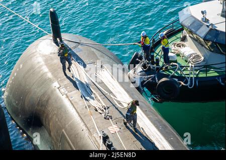 PERTH, Australia (19 aprile 2022) il sottomarino Royal Australian Navy Collins-Class HMAS Farncomb (SSG 74) parte dal sottomarino Emory S. Land-class Tender USS Frank Cable (AS 40), 19 aprile 2022. Frank Cable è sulla pattuglia che conduce la manutenzione e la logistica di spedizione a sostegno della sicurezza nazionale nell'area delle operazioni della flotta degli Stati Uniti 7th. (STATI UNITI Foto Navy di Mass Communication Specialist 3rd Classe Henry Liu/ rilasciato) Foto Stock