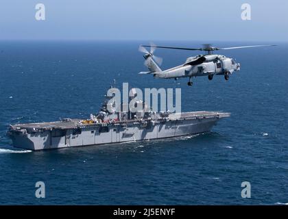 Oceano Pacifico, Stati Uniti. 16 aprile 2022. Un elicottero della Marina degli Stati Uniti MH-60R Sea Hawk, assegnato a Helicopter Maritime Strike Squadron 35, sorvola la nave d'assalto anfibio di classe Wasp USS Tripoli durante le operazioni di routine con la flotta 3rd, il 16 aprile 2021 nell'Oceano Pacifico. Credit: MC3/Dario/Nico/Nico Live News Foto Stock