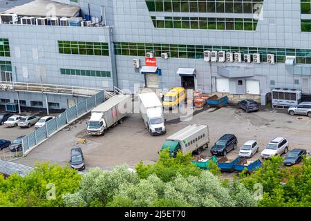 Kemerovo, Russia - 24 giugno 2021. Un grande edificio con automobili e camion di scarico, il cortile di un centro commerciale multi-livello o un magazzino di prodotti Foto Stock