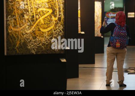 Jakarta, Indonesia. 22nd Apr 2022. Un visitatore scatta una foto di una pittura di calligrafia d'arte contemporanea alla mostra internazionale di calligrafia d'arte contemporanea "The Power of Quran" che si tiene presso il Jakarta Islamic Center, a nord di Jakarta. La mostra, Che è stato tenuto dal Jakarta Center for Islamic Studies and Development, si prevede di essere in grado di riempire l'alfabetizzazione visiva, in particolare da'wah e syiar attraverso l'arte. Questa mostra è stata frequentata da 102 artisti calligrafici provenienti da 25 paesi e può anche essere goduto virtualmente con un approccio interattivo 3D. (Foto di Kuncoro Widyo Rumpoko/Pacific Foto Stock